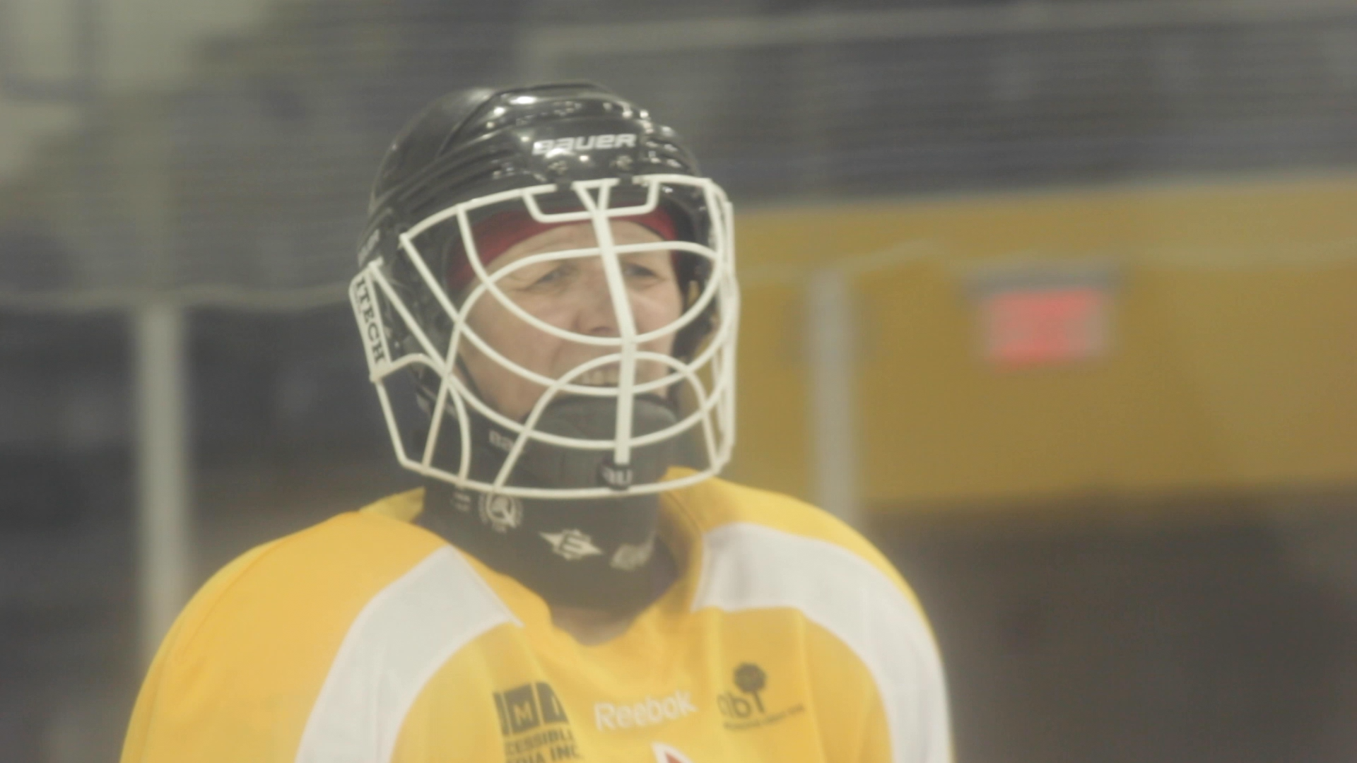 Megan, a white woman wearing a yellow hockey jersey and a black helmet with a white face guard.